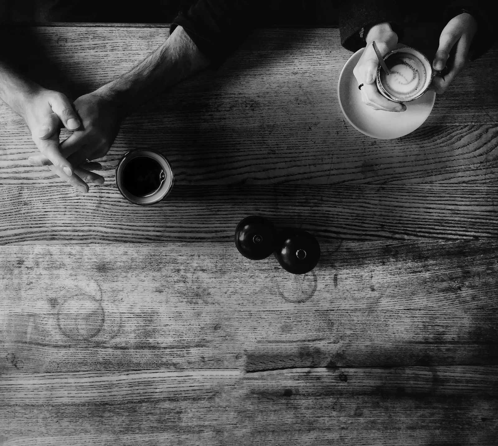 Zwei paar Hände mit Kaffeetassen auf einem Holztisch