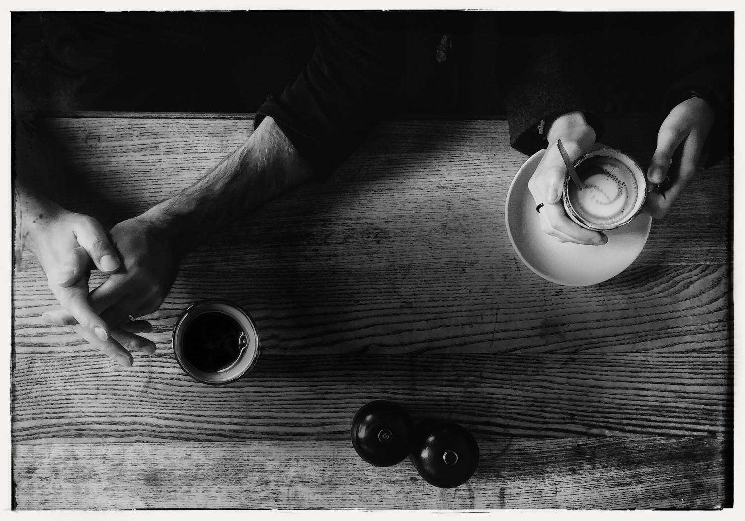 Zwei Personen sitzen an einem Tisch jeweils mit einer Tasse Kaffee vor sich