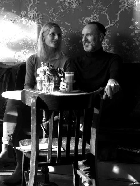 Mike Uhl und Bettina Hinz-Uhl nebeneinander sitzend an einem Bistrotisch
