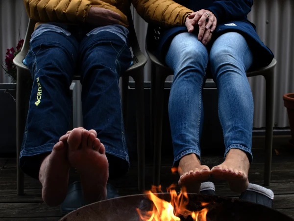 Mike Uhl und Bettina Hinz-Uhl mit nackten Füßen an einem wärmenden Feuer